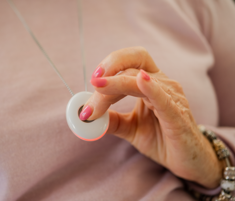 An elderly woman's hand activates her Freedom Medical Alarm.