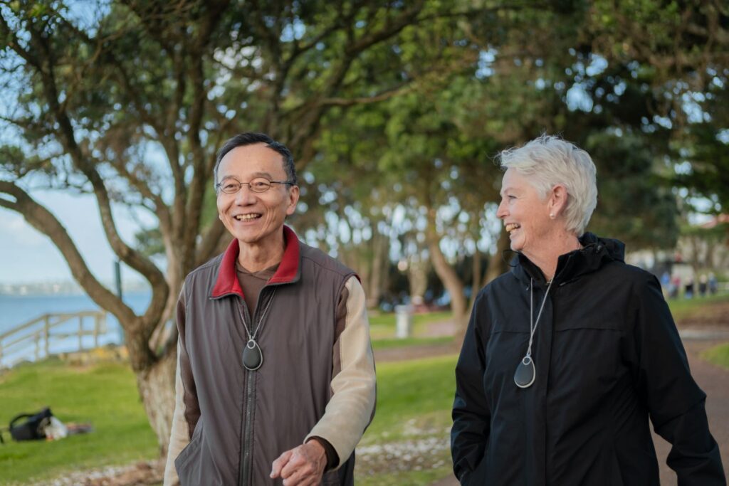 Man and woman walk outside while wearing GO Pendants.